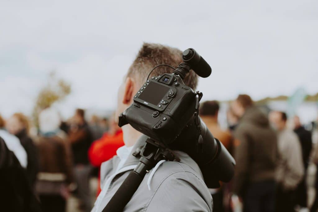 man holding camera with a crowd of people in the background